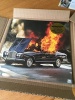 Album cover with a classic black convertible car with the hood open and flames billowing out from the seats.